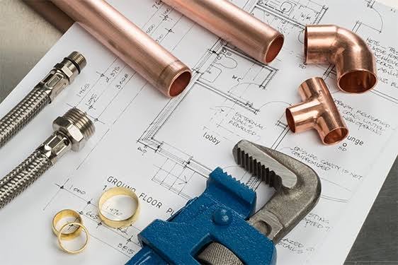 Plumbing plans, copper pipe, fittings, and tools representing job costing and project planning